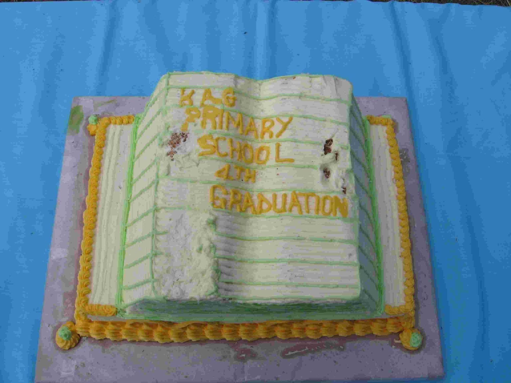 A graduation cake shaped as an open book iced with KAG Primary School graduation