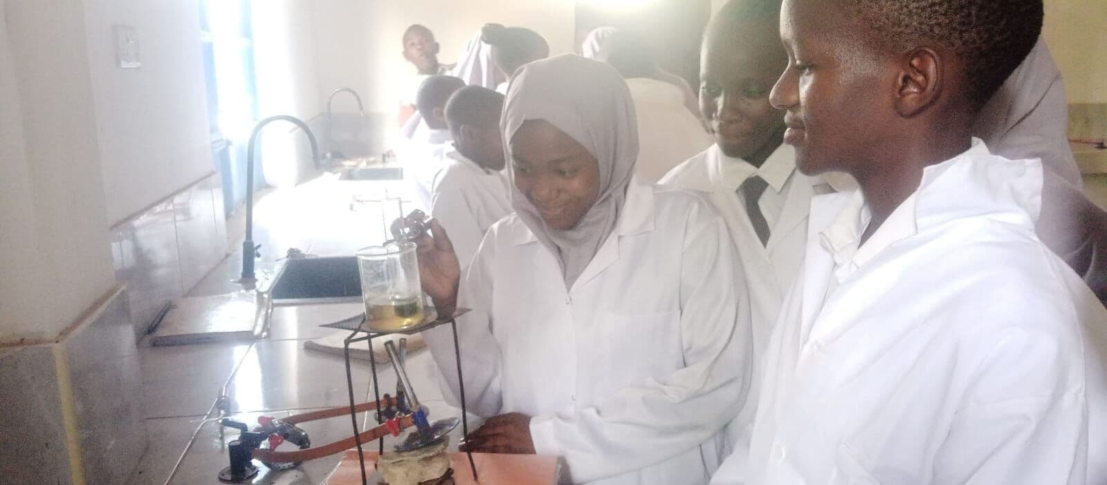 Learners in lab coats during a science practical