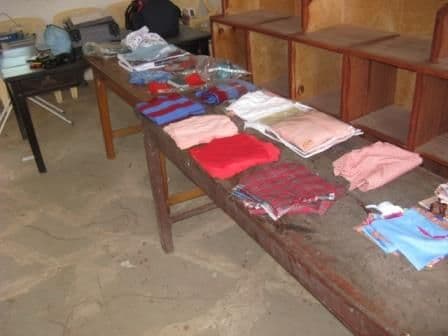Piles of cut fabric pieces in different colours laid out along a wooden table