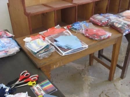 Clear plastic bags of cut fabric pieces on a table beside scissors and coloured pens
